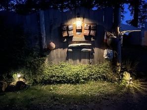 A rustic wooden structure with a wall decorated with various items, including a hanging basket and a bench. - So Damn Lucky Glamping (Ucluelet)
