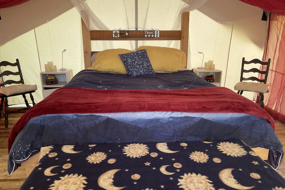Una cama con dosel, una mesita de noche, una silla y una mesita auxiliar.