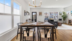 Un comedor con una mesa de madera, sillas negras y una araña.