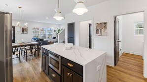 Una cocina moderna con encimera de mármol, electrodomésticos de acero inoxidable e iluminación colgante.