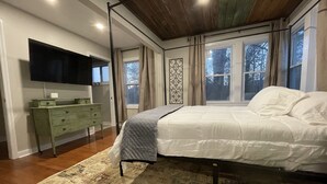 Ein Schlafzimmer mit Bett, Kommode, Fernseher und Fenster.