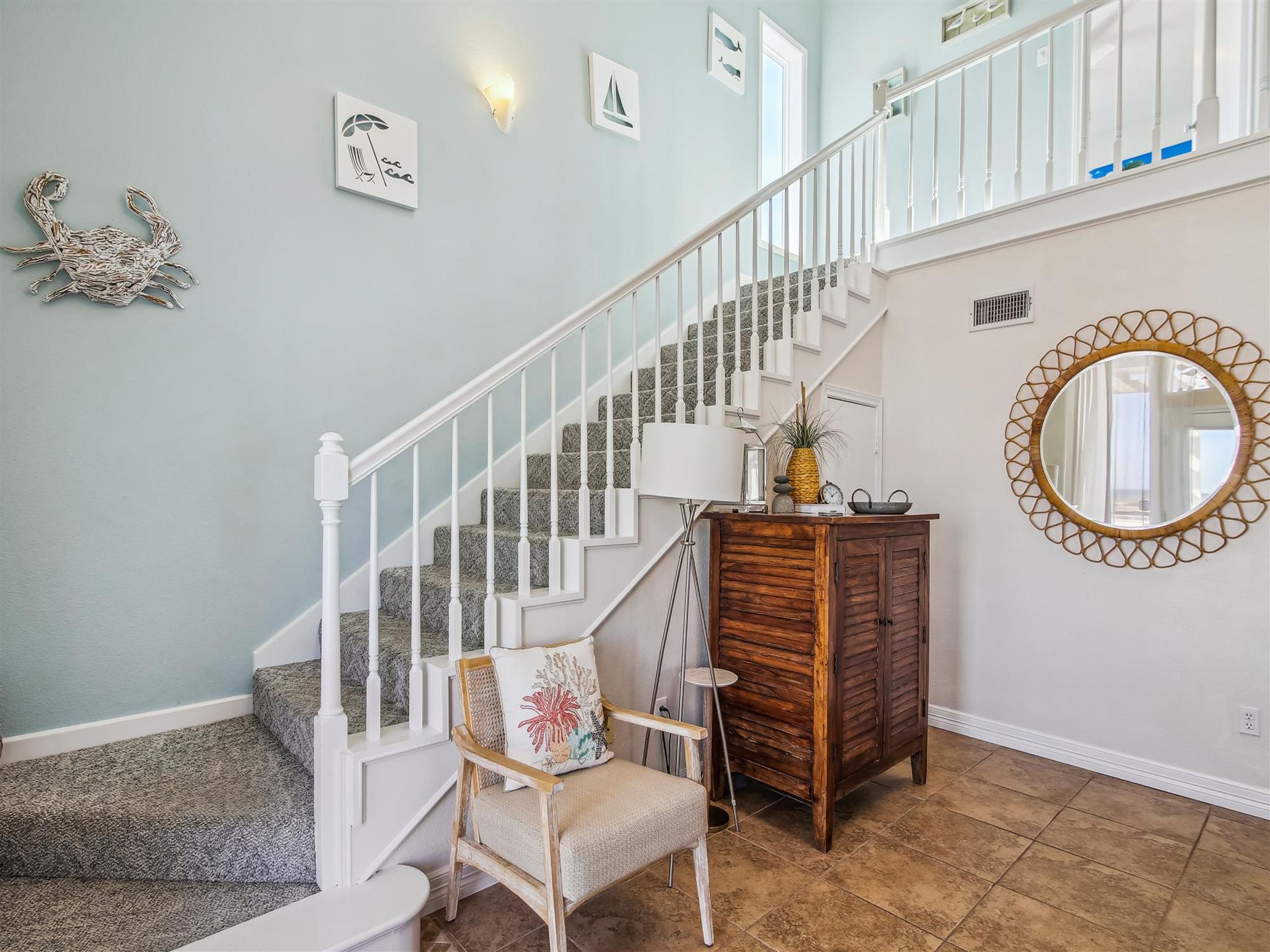 A staircase with white railings and a wooden cabinet with a mirror.