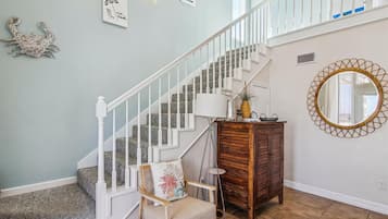 A staircase with white railings and a wooden cabinet with a mirror.