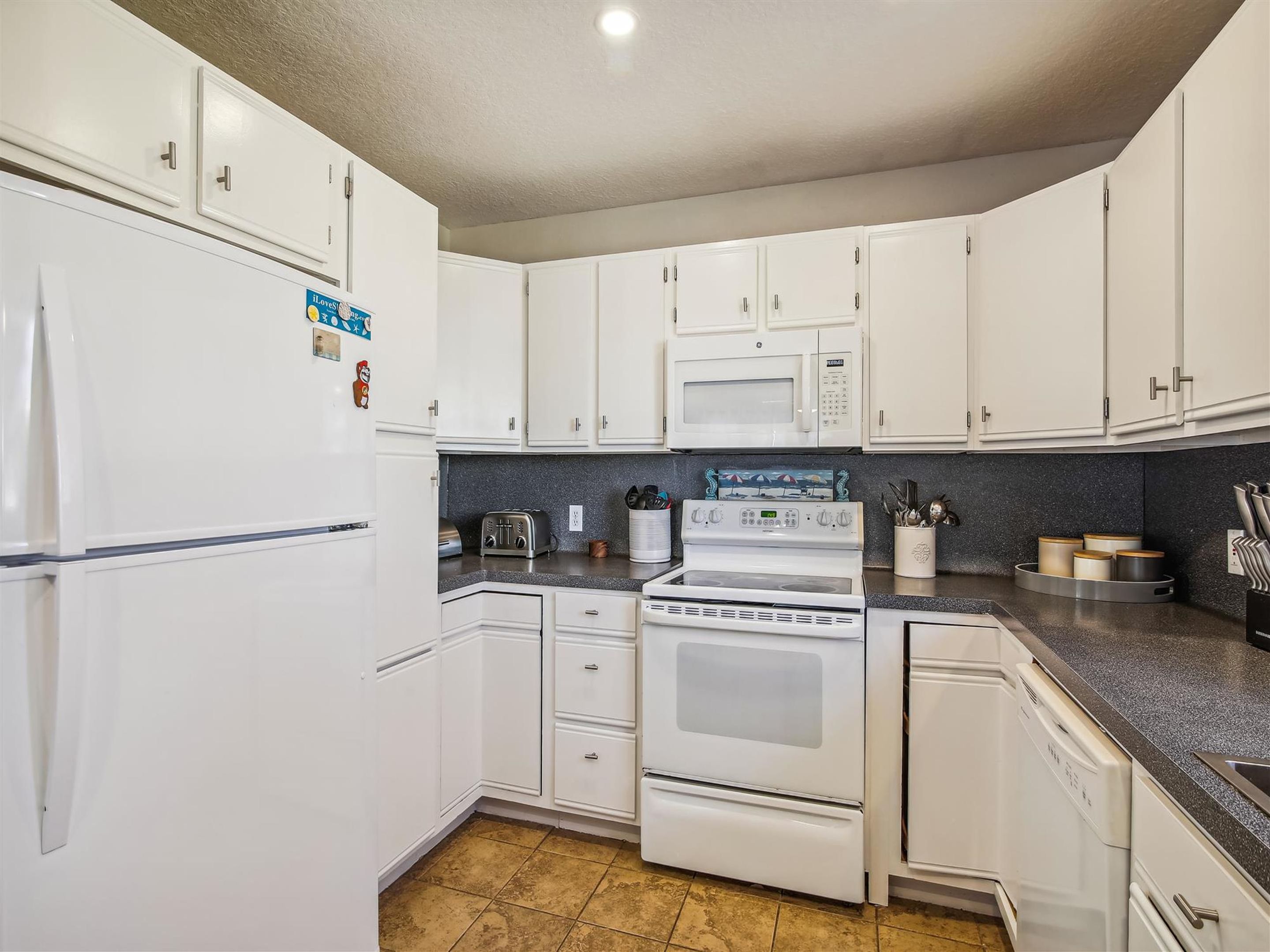 A kitchen with white cabinets, a microwave, a stove, and a toaster.