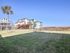 Une propriété située en bord de mer, comprenant une grande maison, une terrasse couverte et une pelouse.