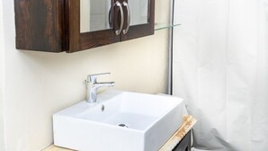 A bathroom with a white sink, dark wooden cabinet, and a toilet. - Cozy Nook nestled in the Santa Cruz Valley. 
Queen sized bed Hot and cold shower (Santa Cruz)