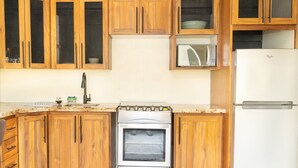 A kitchen with wooden cabinets, a stove, a microwave, and a refrigerator. - Cozy Nook nestled in the Santa Cruz Valley. 
Queen sized bed Hot and cold shower (Santa Cruz)