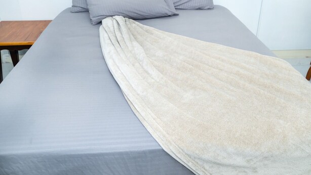 A bed with a grey sheet and pillows, a beige blanket, and a wooden nightstand. - Cozy Nook nestled in the Santa Cruz Valley. 
Queen sized bed Hot and cold shower (Santa Cruz)