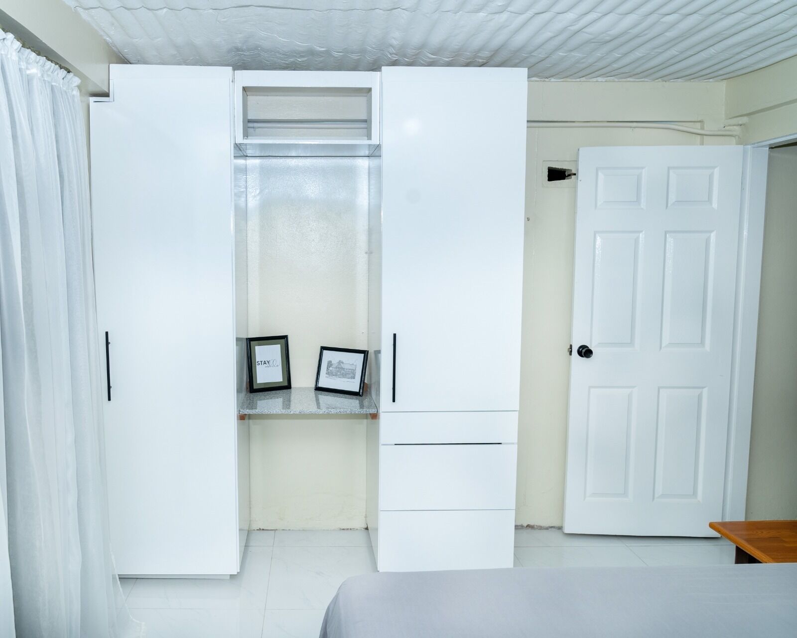 Une chambre à coucher avec un lit, une armoire, une porte et une petite table.