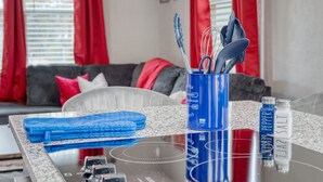 A kitchen counter with a blue container holding utensils, a blue towel, and salt and pepper bottles. - Cozy Home with City Views (Columbus)