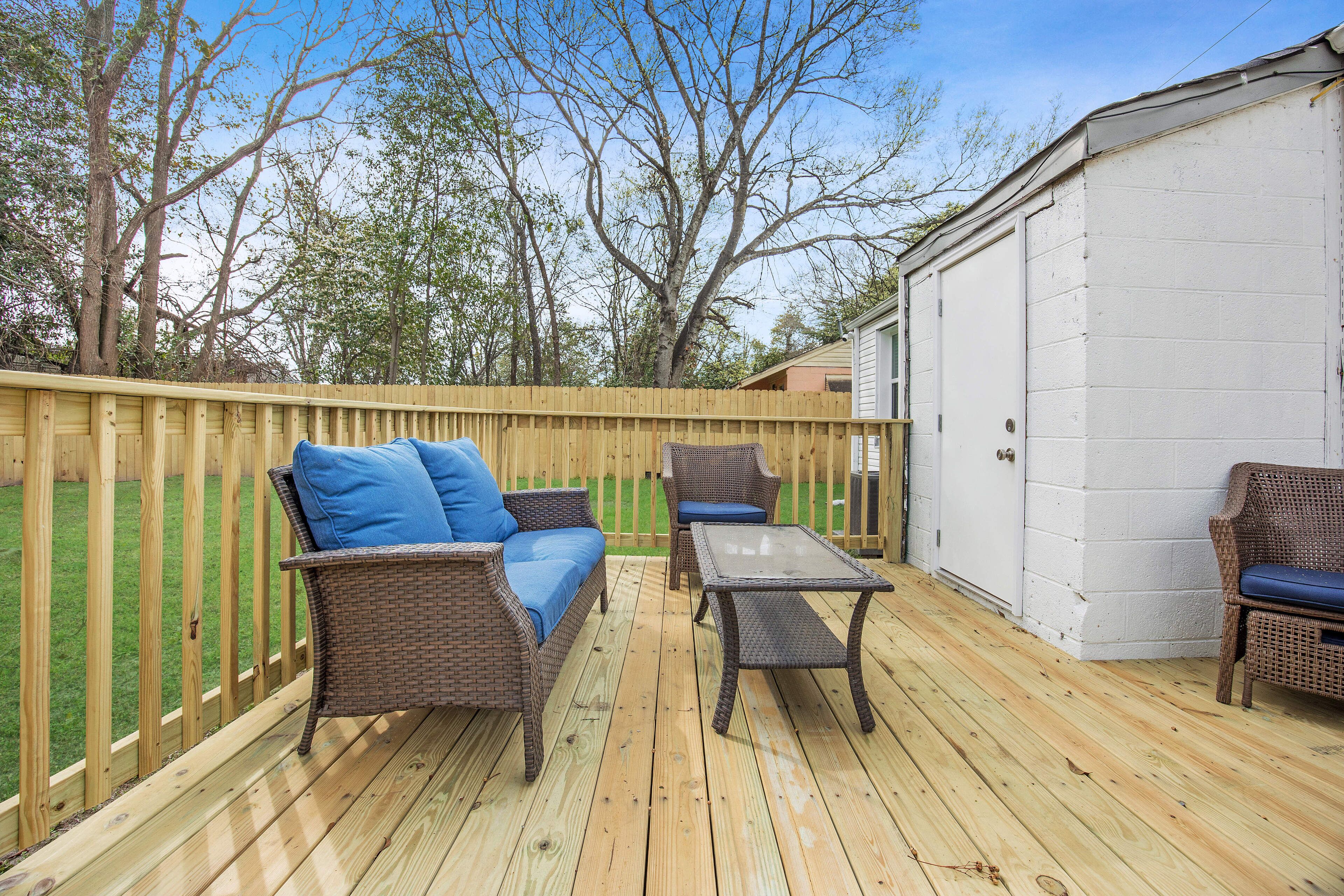 Une terrasse extérieure avec des meubles en osier, une table et un abri de jardin en arrière-plan.