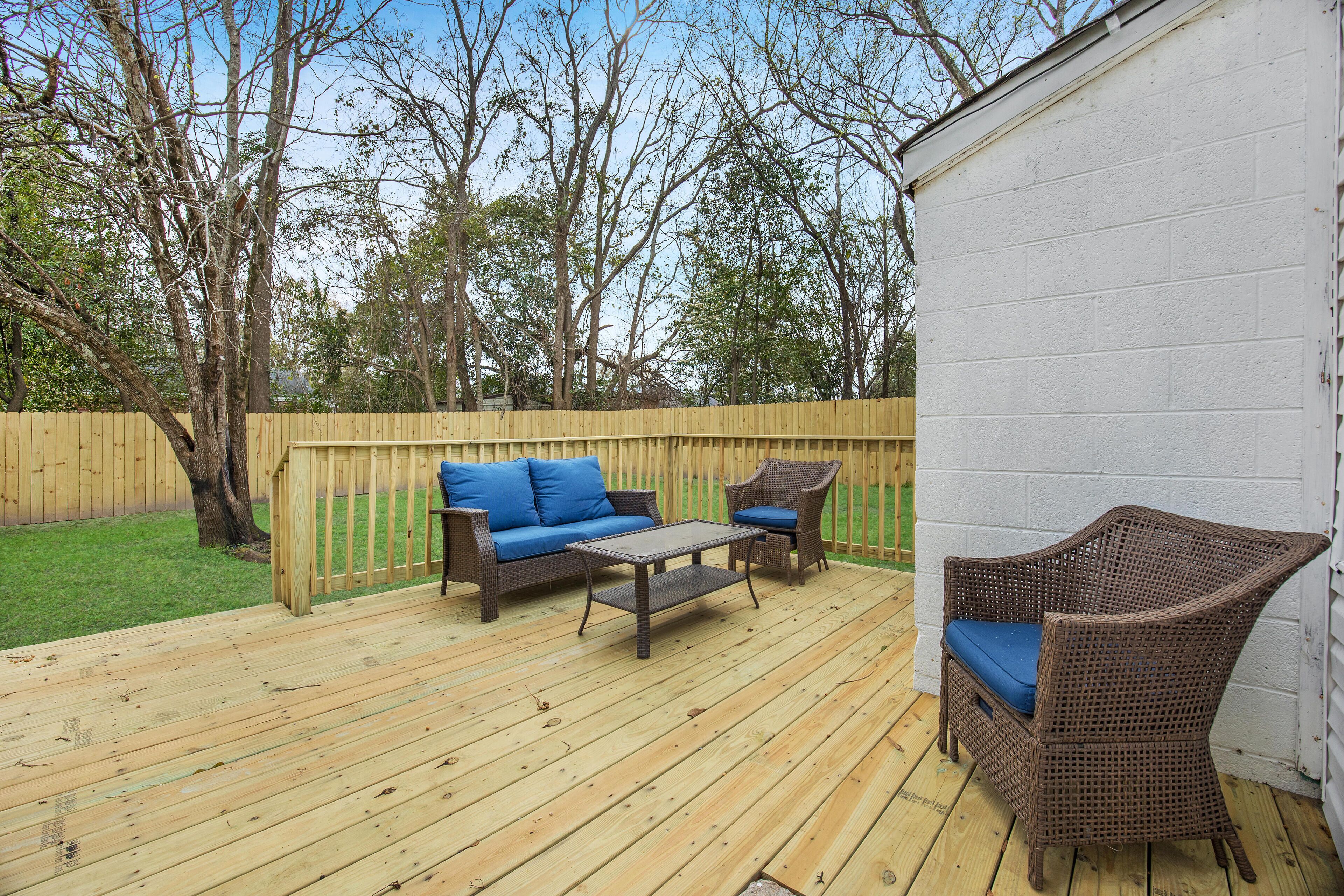 A wooden deck with outdoor furniture, including a sofa and chairs, and a small table.