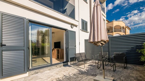 Eine moderne Terrasse mit Schiebeglastür, Sitzgelegenheiten im Freien und einem Fernseher.