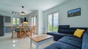 Un salon moderne avec un canapé, une table à manger et des chaises, et une cuisine en arrière-plan.