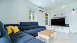 Un salon moderne avec un canapé d’angle, une table basse, un téléviseur et des étagères intégrées.