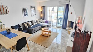 A modern living room with a sofa, coffee table, and dining area.