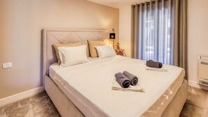 Een net opgemaakt bed met hoofdeinde, kussens en een opgerolde handdoek erop.