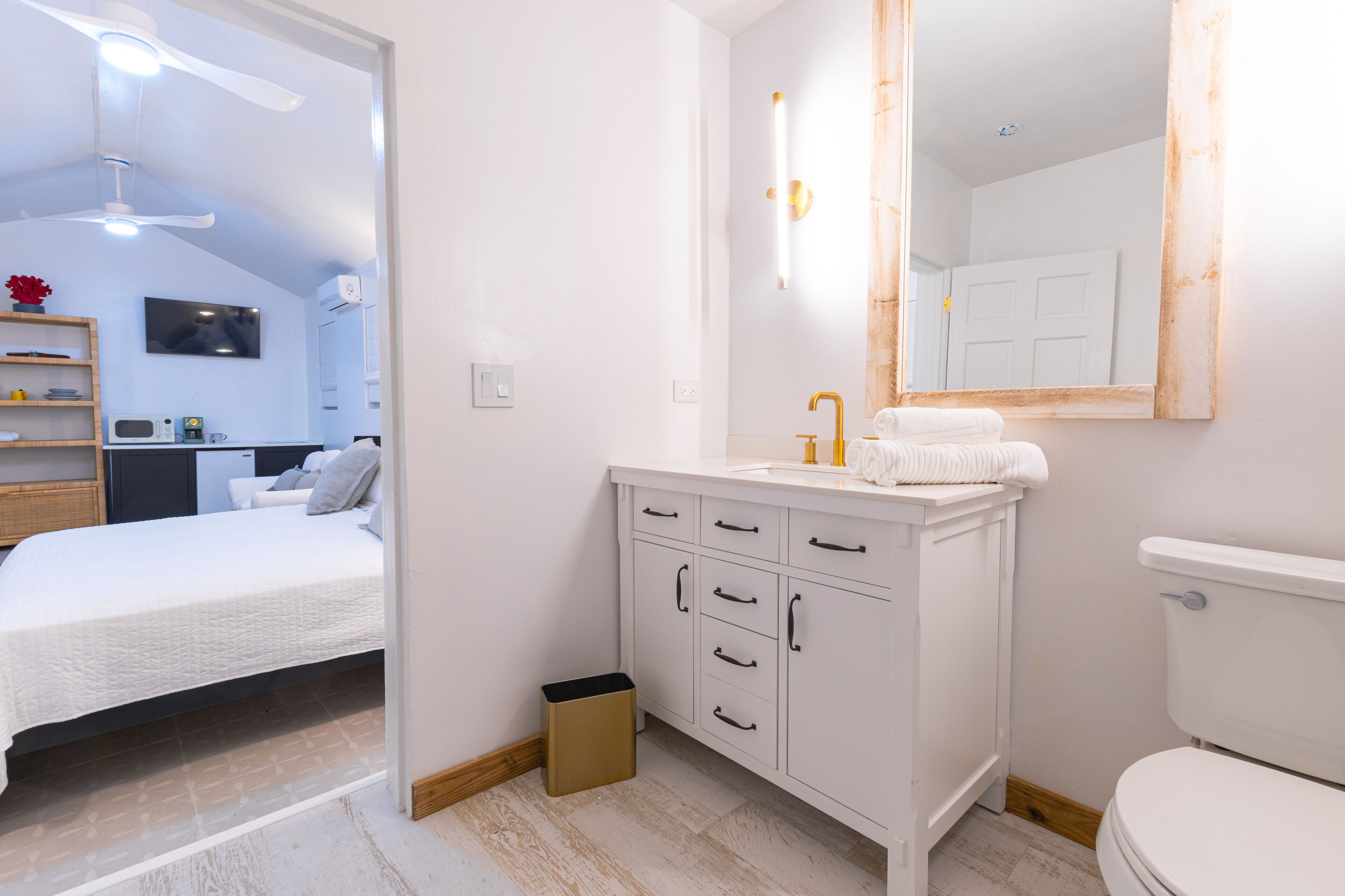 A modern bathroom with a white vanity, a large mirror, and a toilet.