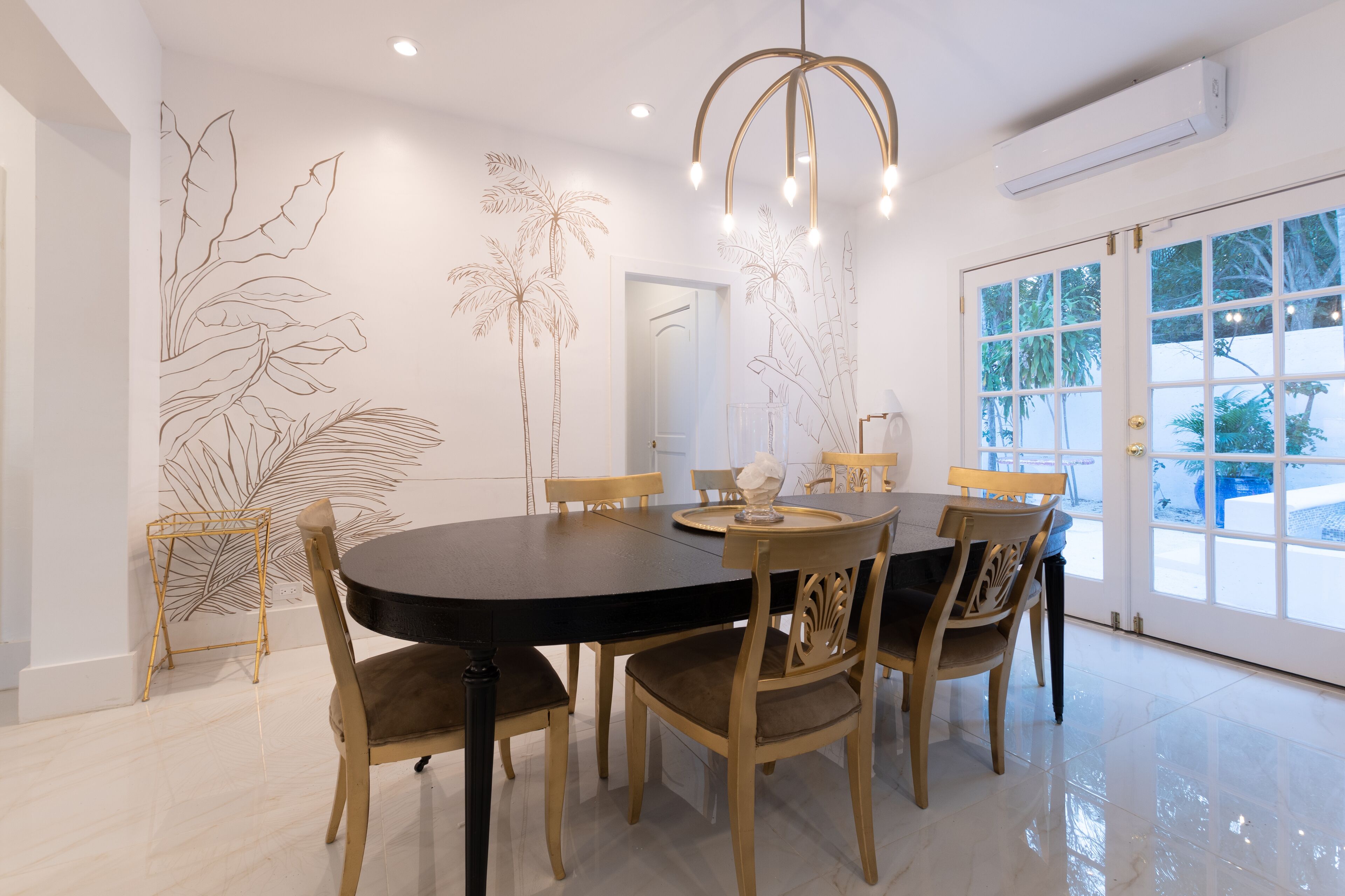 Zona pranzo con tavolo rotondo, sei sedie, un lampadario e decorazioni murali.