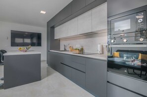 Enjoy cooking in this well-equipped kitchen with a central island, oven, and flat-screen TV.