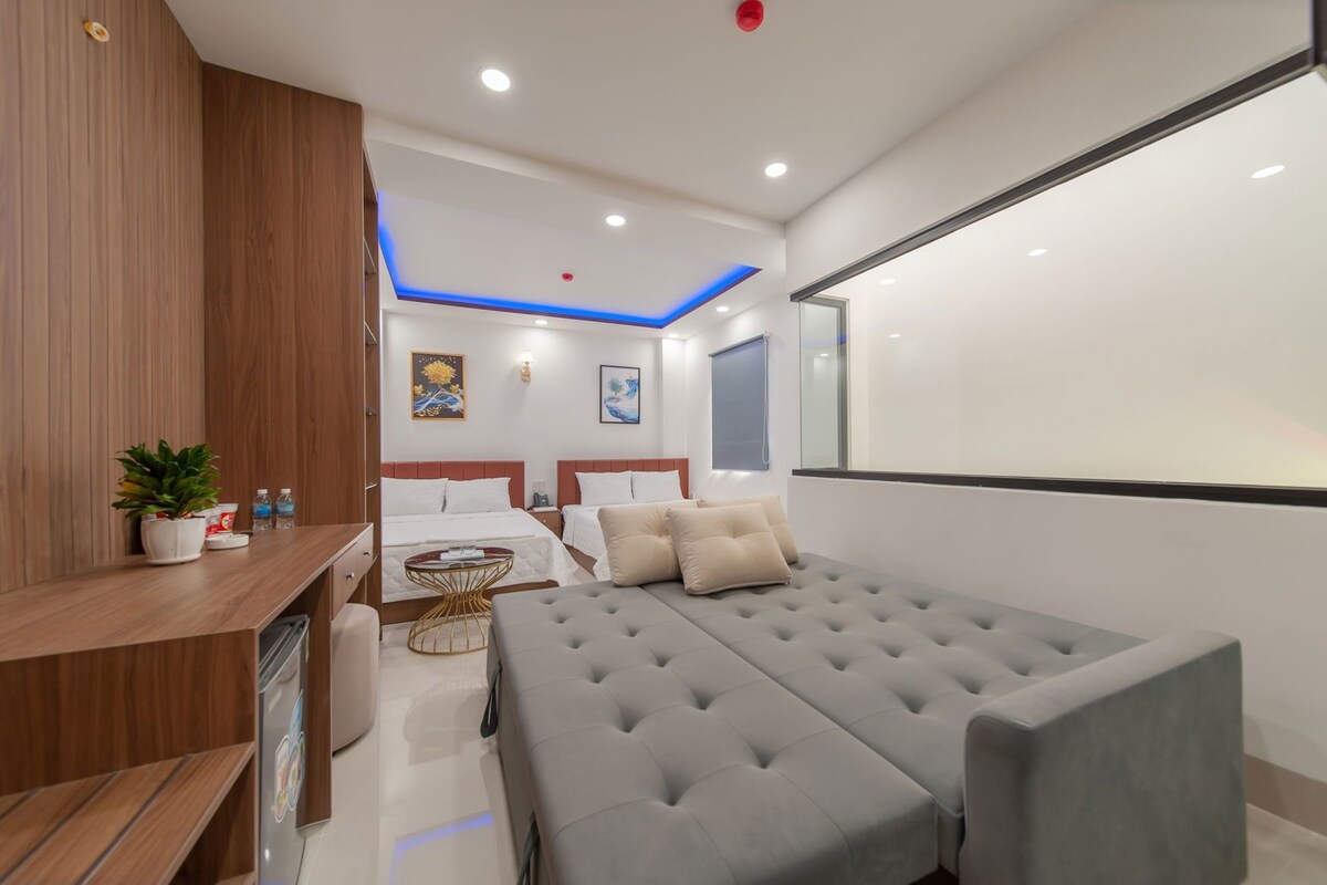 Una habitación de hotel moderna con una cama grande, un escritorio, una silla y una pequeña mesa con una planta.