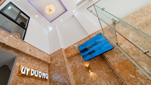Un interior moderno con suelo de mármol, barandilla de cristal y una pantalla digital.