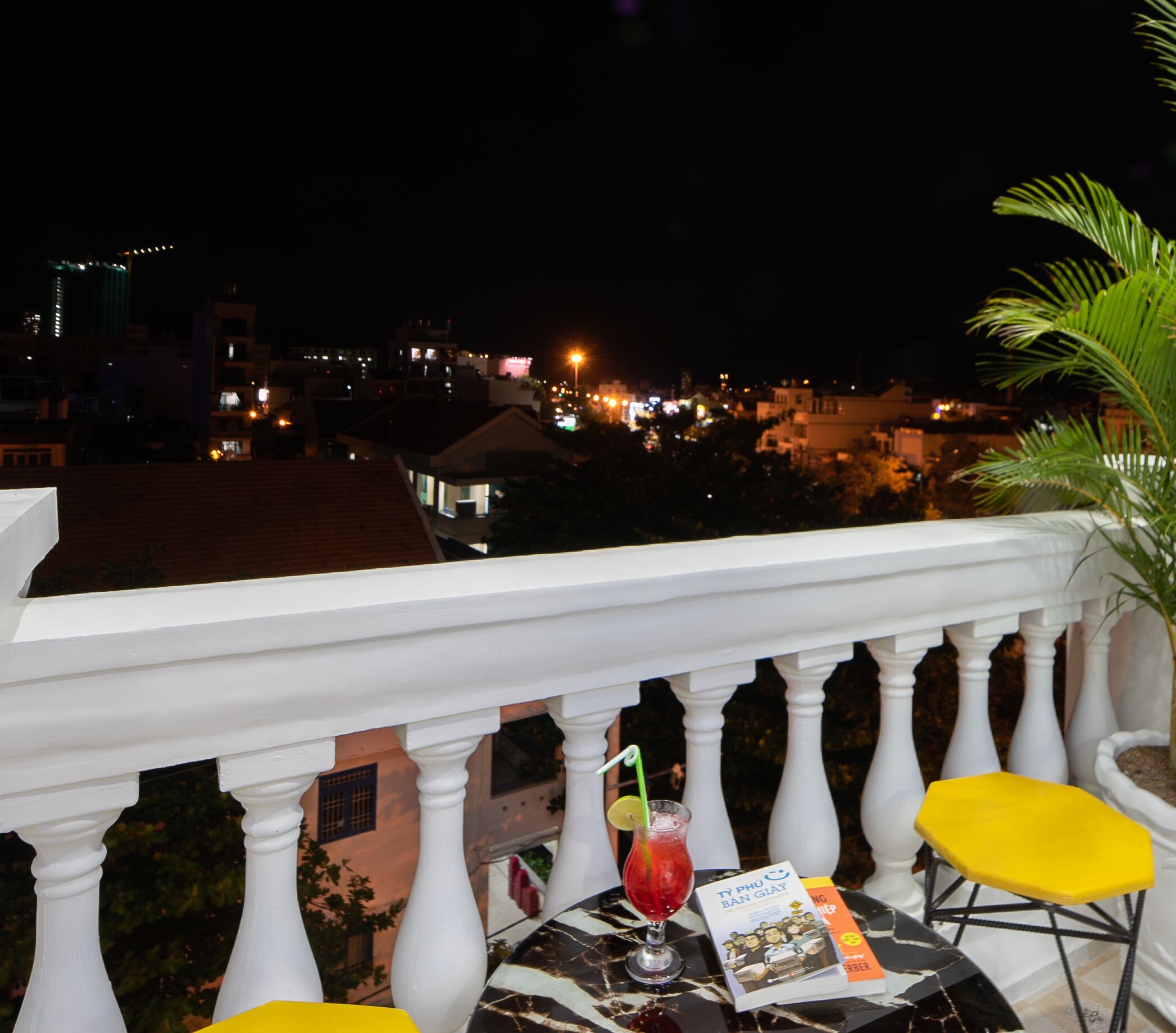 A balcony with a table, chairs, a drink, and a menu.