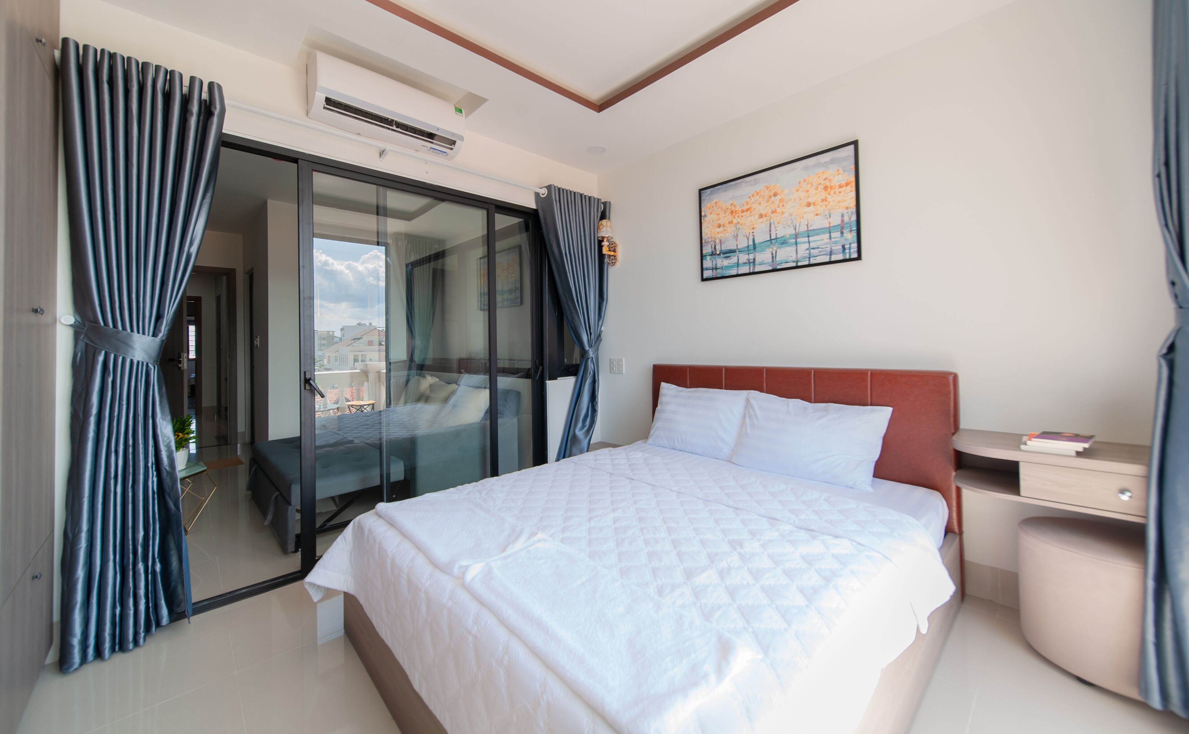 Une chambre d’hôtel avec un lit, un bureau, une chaise, une fenêtre avec des rideaux et un tableau au mur.