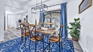 A dining area with a wooden table, chairs, and a blue patterned rug. - The Mid-Century Retreat (Lansing)