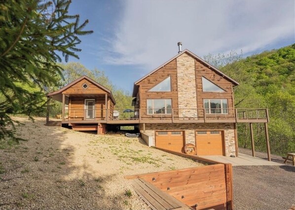 Two wooden cabins with a stone facade, a covered deck, and a gravel driveway.