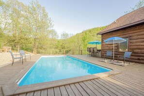 Relax by the pool surrounded by a deck with comfortable seating and umbrellas.