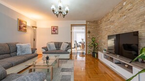 A modern living room with a sofa set, a coffee table, a TV, and a brick wall. - Amazing apartment in Gracac (Gracac)