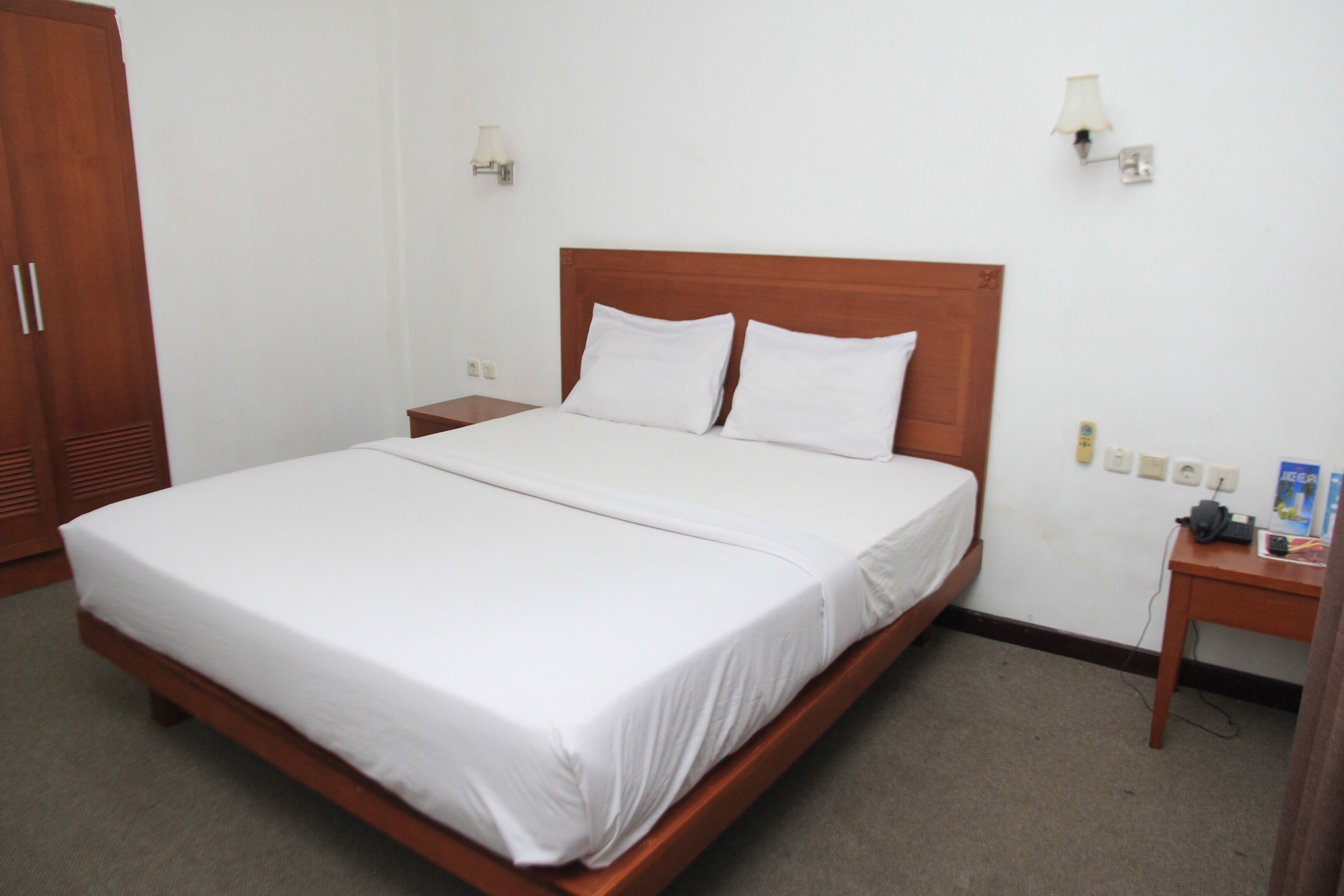 Una cama bien hecha con sábanas blancas en una habitación de hotel.