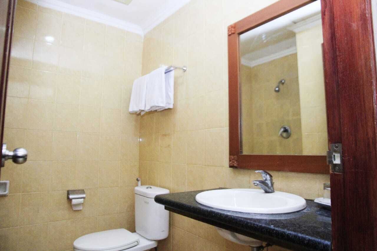 A bathroom with a toilet, sink, and mirror.