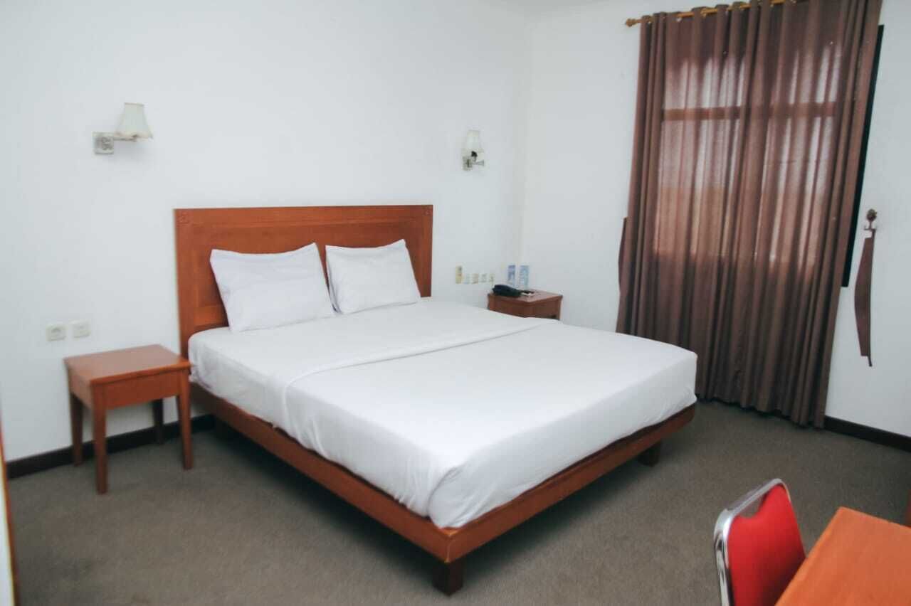 Une chambre d’hôtel avec un lit en bois, une table de chevet, une table et une chaise.