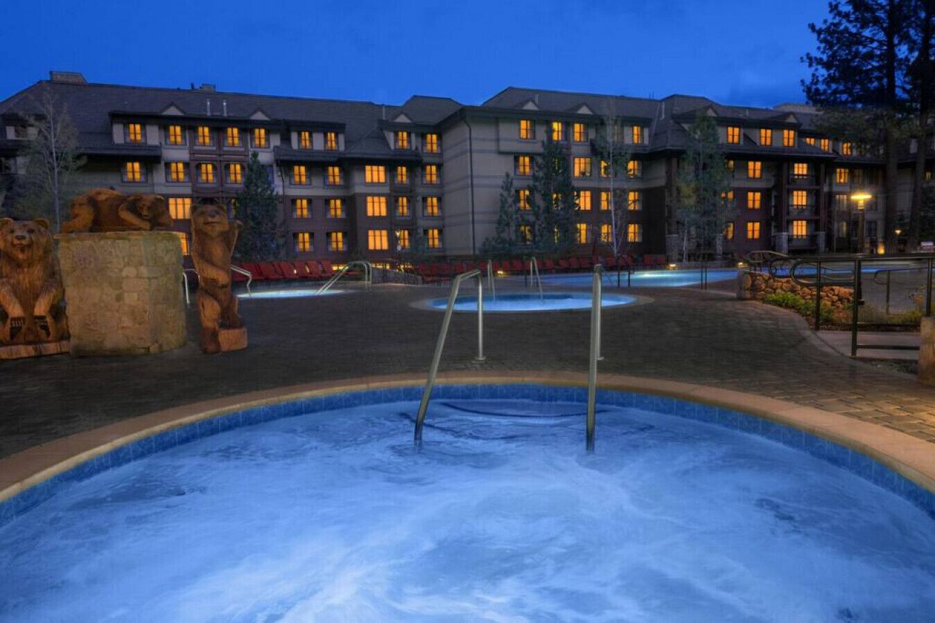 A hotel with multiple floors, outdoor swimming pool, and stone lion statues.