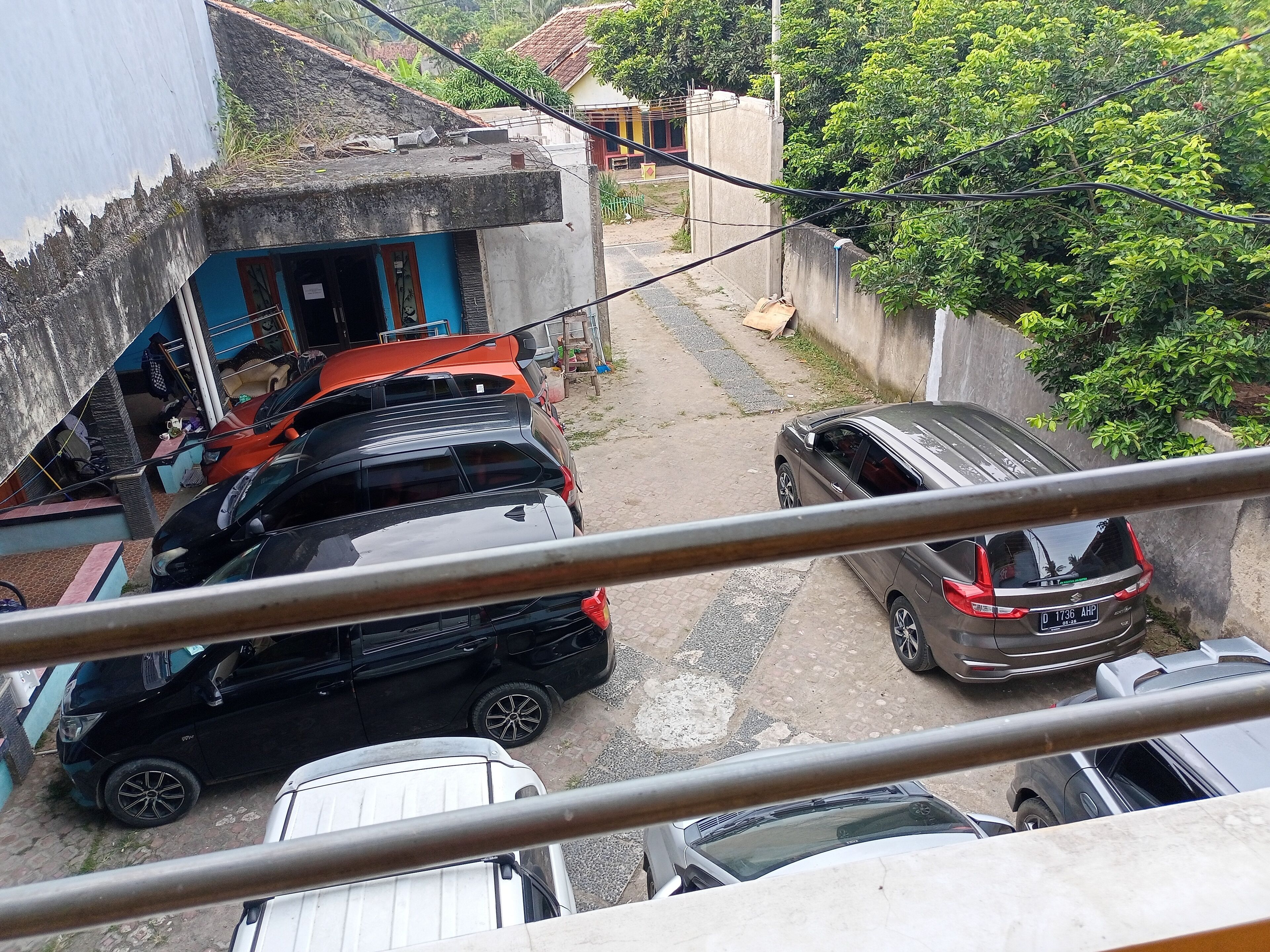 Una calle estrecha con autos estacionados y un edificio de fachada azul.