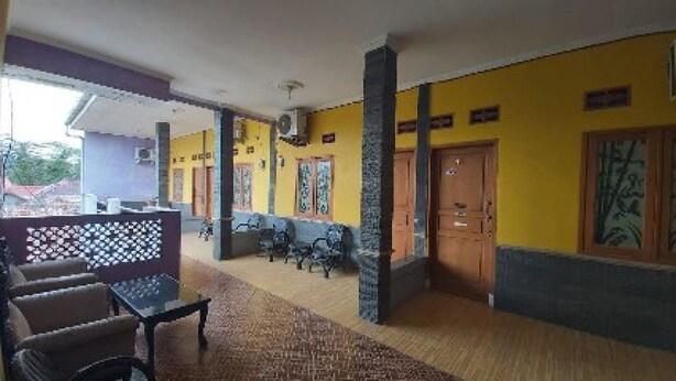 Un hall de hotel con una zona de estar, un mostrador de recepción y una escalera que conduce a los pisos superiores.