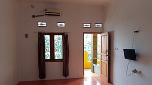 Una habitación con cama, aire acondicionado, televisor montado en la pared y ventana con cortinas.