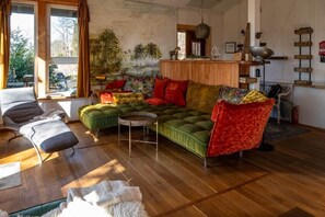 A cozy living room with a green sofa, red and yellow cushions, a wooden coffee table, and a chair.