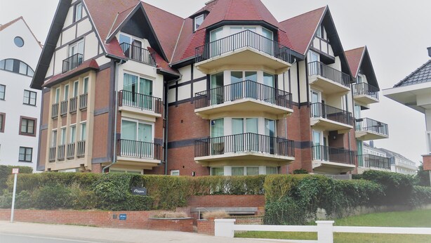 Un immeuble résidentiel à plusieurs étages, doté d’une tourelle d’angle remarquable, de grandes fenêtres et de balcons.