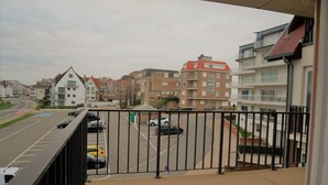 Un balcon donnant sur un parking et des immeubles.