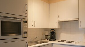 Une cuisine moderne avec des meubles blancs, un four à micro-ondes de marque Bosch, une machine à café et un lave-vaisselle.