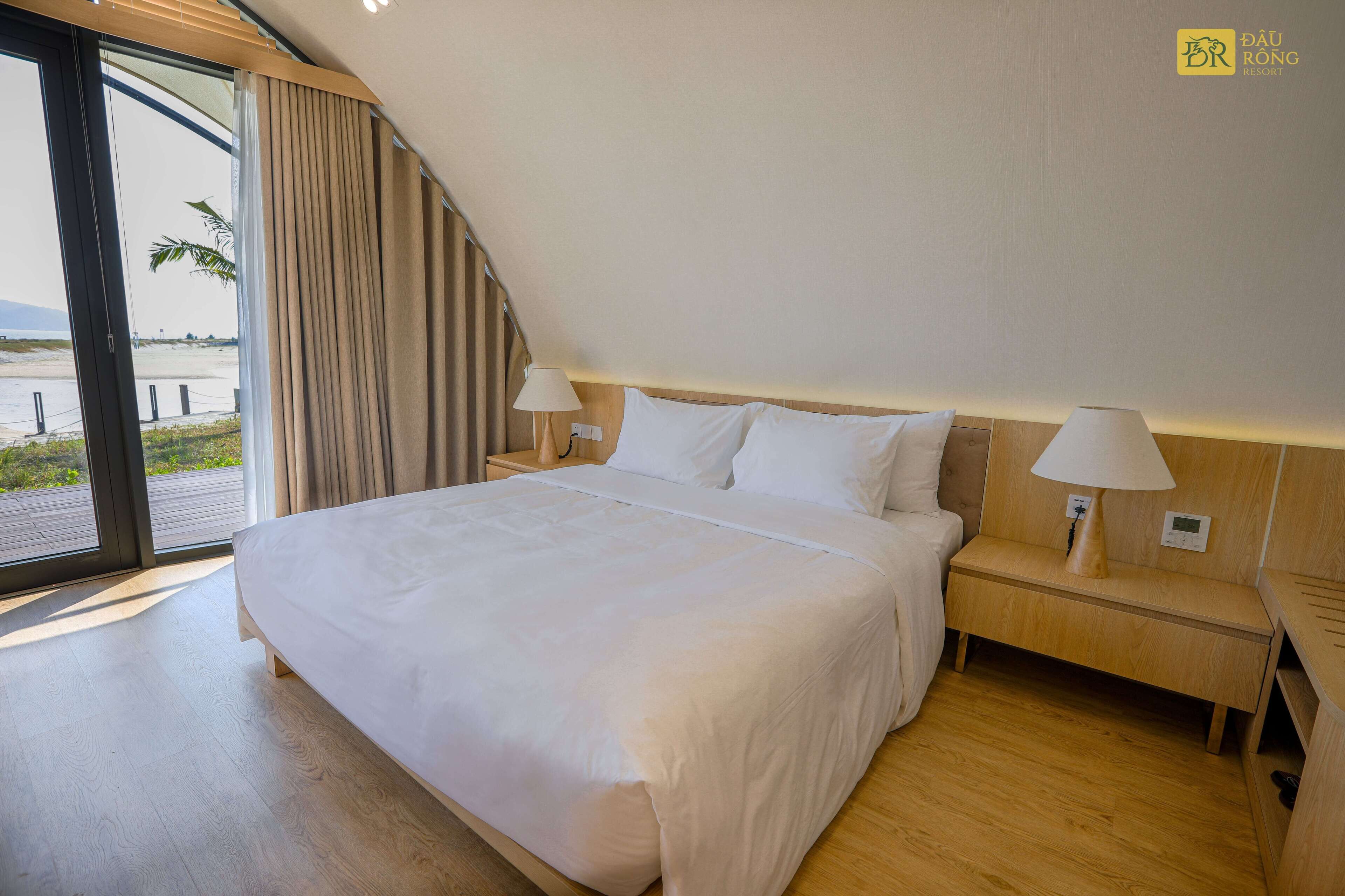 Une chambre d’hôtel avec un grand lit, des tables de chevet en bois et une vue sur la plage.