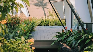A rooftop garden with a wooden deck, surrounded by lush greenery and flowering plants. - Dau Rong Resort (Cai Chien)