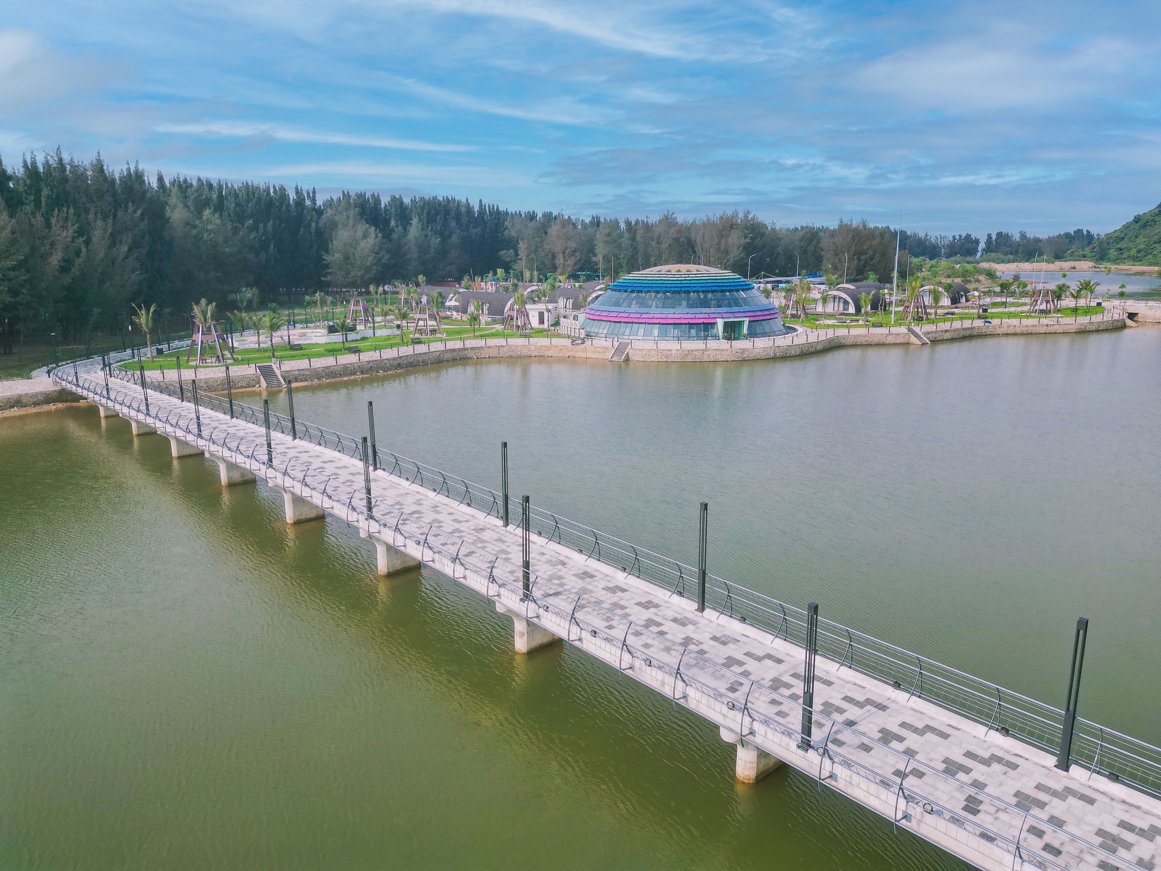 A bridge over a body of water with a modern building in the background.