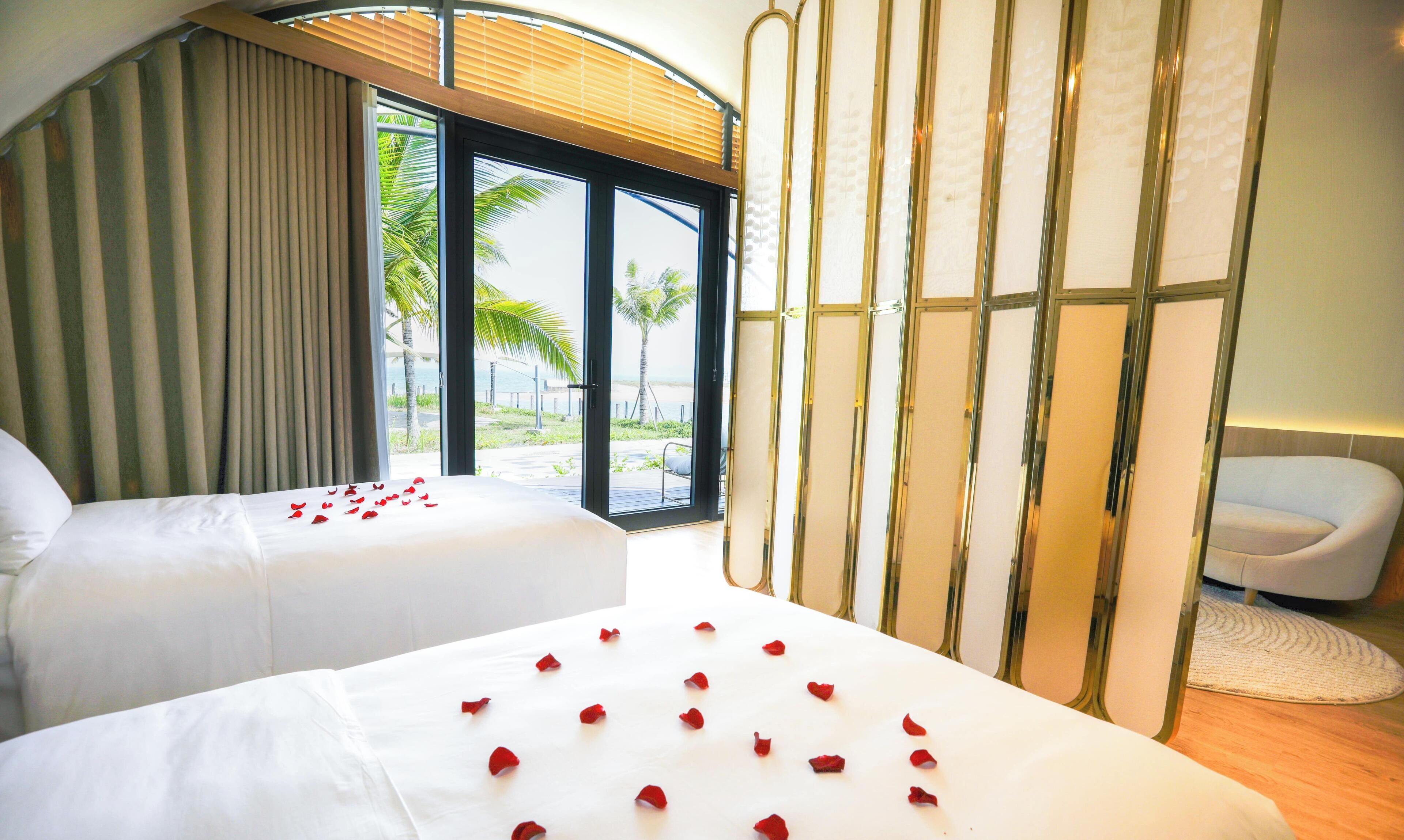 A hotel room with two beds, a large window with a view of palm trees, and a modern interior design.