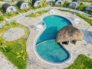 A resort with a large swimming pool, thatched-roof structures, and lush greenery. - Dau Rong Resort (Hai Ha)