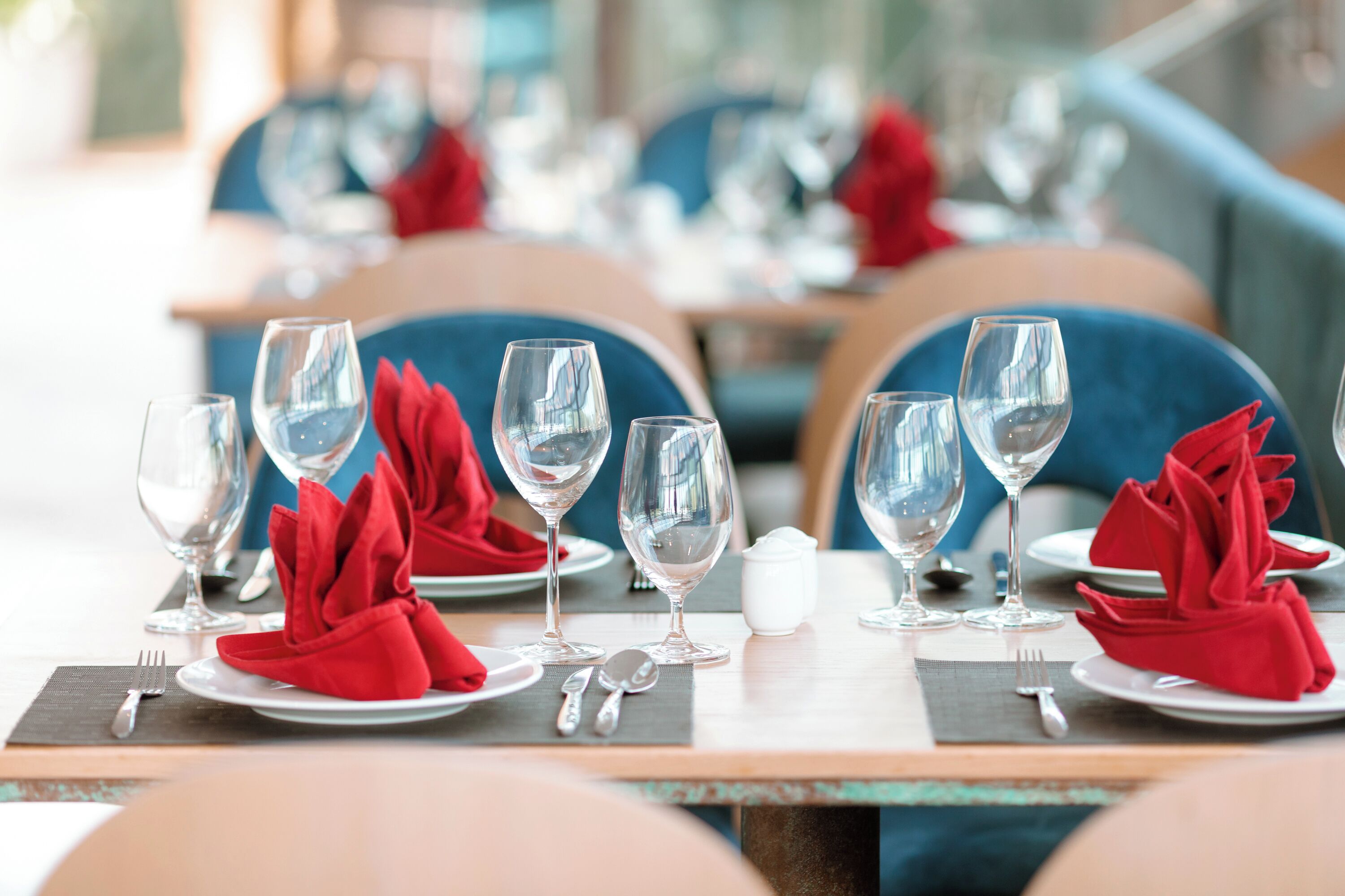 A dining table set with multiple wine glasses, red napkins, and silverware.