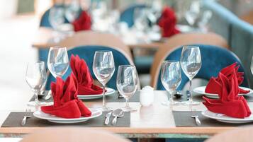 A dining table set with multiple wine glasses, red napkins, and silverware.